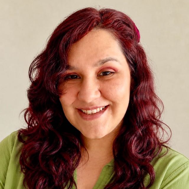 Sofía Zúñiga sonriendo, con el pelo rojizo ondulado y blusa verde